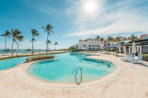 a swimming pool at the beach with palm trees and buildings at NEW 2BR Apt w Jacuzzi Punta Palmera CBA in Punta Cana
