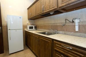 Relax inn Apartment - Fahaheel في الكويت: مطبخ مع ثلاجة بيضاء ومغسلة