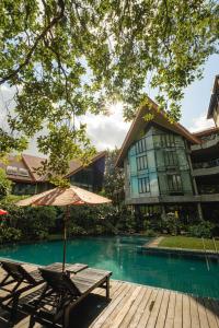 stół i parasol obok basenu w obiekcie Kireethara Boutique Resort w mieście Chiang Mai