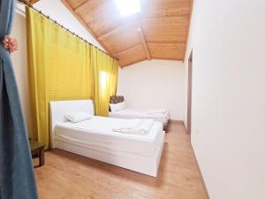 Habitación con 2 camas y cortina amarilla en Jeju Gillime Pension, en Jeju