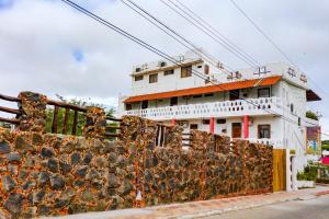 a white building with a fence in front of it at Royal Galápagos Inn in Puerto Baquerizo Moreno