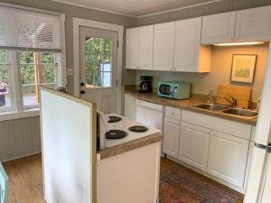 a kitchen with white cabinets and a white refrigerator at Adorable Cottage Among Trees Close To Everything in Vancouver