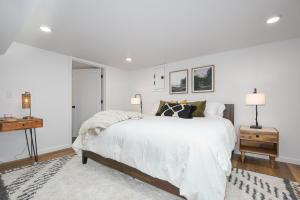 a white bedroom with a large bed and two lamps at Bright & Modern Basement Apartment Dt N'hood in Vancouver