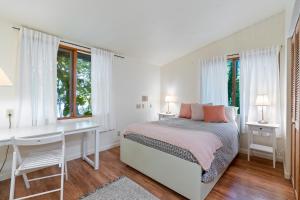 Habitación blanca con cama, escritorio y ventanas en The Riverfront Retreat-woods Landing, en Vancouver