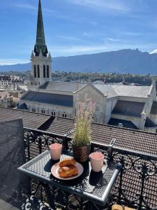 a table with a plate of food on a balcony with a church at Coeur d'Aix, vue splendide et cachet in Aix-les-Bains