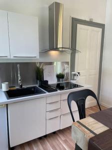 a white kitchen with a sink and a stove at Coeur d'Aix, vue splendide et cachet in Aix-les-Bains