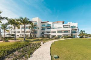 un gran edificio blanco con palmeras delante en Ocean View 1 BR Apartment at Punta Palmera DB7 en Punta Cana