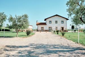 a large white house with a gravel driveway at LA MASSARÌA agriresort in Orta Nova