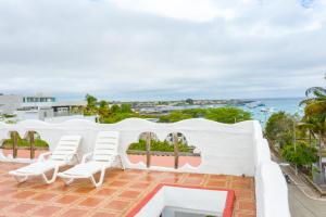 a patio with white chairs and a pool and the ocean at Royal Galápagos Inn in Puerto Baquerizo Moreno +78 photos