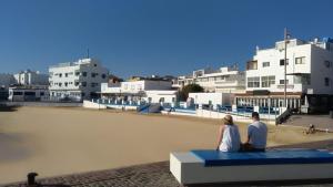a couple sitting on a bench in front of a beach at Casa Bubal by Best Holidays Fuerteventura in Corralejo