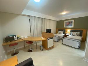 a hotel room with two beds and a desk and a table at Bienal First Class Flat Service - UH607 in São Paulo