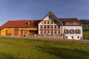 un grand bâtiment avec un champ devant lui dans l'établissement Landgasthaus Neues Bild, Eggerstanden, à Appenzell