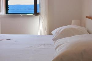 a bedroom with a white bed and a window at Guest House Marija in Bol