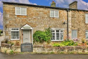 een oud bakstenen huis met een witte deur bij Finest Retreats - Cloggers Cottage in Darley