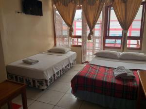 2 camas en una habitación con ventanas en Hostal Miconia, en Puerto Ayora