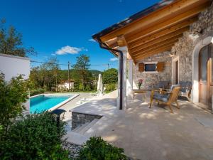 eine Terrasse mit Pool und ein Haus in der Unterkunft VillaNuova in Šušnjevica