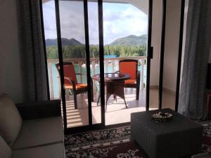 uma sala de estar com uma varanda com uma mesa e cadeiras em Belle Rose Vue guest house em Baie Sainte Anne