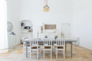 uma sala de jantar com uma mesa cinzenta e cadeiras brancas em Tenuta Pinto em Mola di Bari