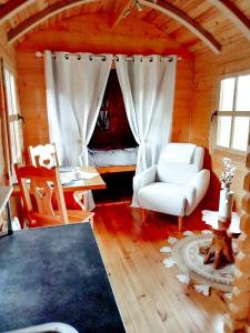 a living room with a white chair and a bed at Le studio du Pressoir in Gisay