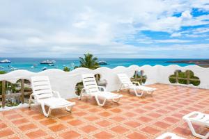 een groep witte stoelen op een patio met uitzicht op de oceaan bij Royal Galápagos Inn in Puerto Baquerizo Moreno