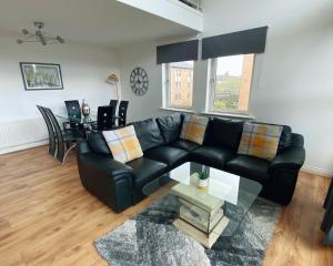 a living room with a black leather couch and a table at The OVO Hydro Penthouse With Free Parking in Glasgow