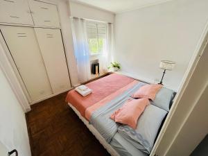 een slaapkamer met een bed met roze lakens en een raam bij Mira Bosques 2 in La Plata