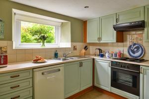 a kitchen with white cabinets and a sink and a window at Finest Retreats - The Cottage at Greystoke in Greystoke +12 photos