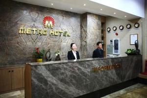 dos personas de pie en el mostrador de recepción de un hotel Metro en Metro Pol Tourist Hotel, en Pyeongtaek