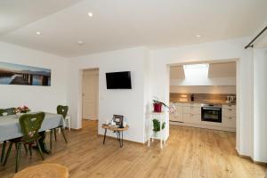 a white living room with a table and a kitchen at FeWo Am Stocket in Gstadt am Chiemsee