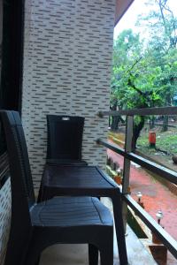 een zwarte stoel op een veranda met een raam bij Hublal cottage in Matheran
