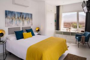 - une chambre dotée d'un grand lit avec des oreillers jaunes et bleus dans l'établissement SUNRISE by Buenavilla, à Playa Blanca