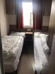 ein kleines Schlafzimmer mit 2 Betten und einem Fenster in der Unterkunft Swift Loire (Field view 78) in Jaywick Sands