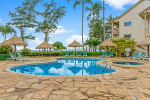 a swimming pool with chairs and umbrellas at a resort at Islander on the Beach 354 in Kapaa