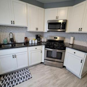 een keuken met witte kasten, een fornuis en een magnetron bij Retreat Suite 4 - Downtown Getaway in Grand Rapids