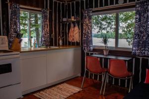 cocina con mesa, 2 sillas y ventanas en Cedar Cabin - North Frontenac Lodge en Ompah