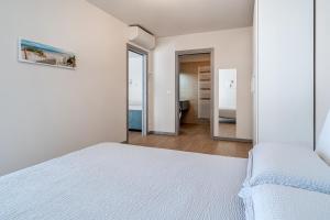 Habitación blanca con cama y espejo en Appartamenti Giotto, en Sesto al Reghena
