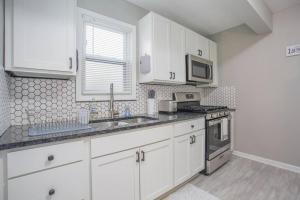 a kitchen with white cabinets and a sink and a microwave at Stunning Couples Retreat - Downtown Getaway in Grand Rapids