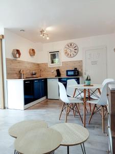 a kitchen with white chairs and a table and a clock at Le pressoir de gisay in Gisay