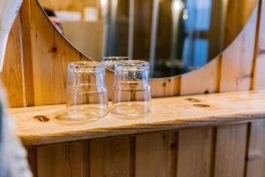 three empty glasses sitting on a wooden table in front of a mirror at Hlíd Cottages in Myvatn