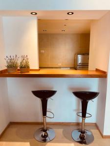 a kitchen with two bar stools under a counter at Tucuman Suite Bariloche in San Carlos de Bariloche