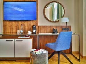 Habitación con escritorio, silla azul y espejo. en EST Grand Hotel Savoy en Budapest