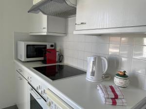 cocina blanca con microondas y cafetera en Ascona: San Materno-Mary en Ascona