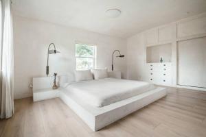a white bedroom with a large white bed and a window at Casa Terra Lumi in Fort Lauderdale