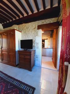 Una sala de estar con un televisor sobre un mueble de madera. en Chambres Résidentielles avec cuisine au Manoir de Mathan à Crépon 5 mn D'Arromanches et 10 mn de Bayeux, en Crépon