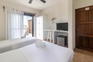 a bedroom with two beds and a desk and a television at Hotel Boutique Pachamama in Mahahual