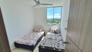 a small room with two beds and a window at APARTAMENTO GIRARDOT BUENA UBICACIÓN in Girardot +8 photos