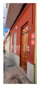 a red building with a wooden door on a street at Dream Escape in Santa Cruz de Tenerife