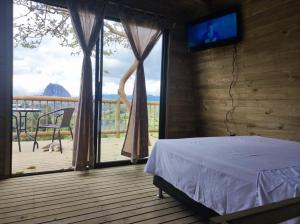 1 Schlafzimmer mit einem Bett und einem Balkon mit einem TV in der Unterkunft Breeze Glamping -Guatape in El Peñol