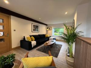 a living room with a black couch and a table at Ty Gwyn Holiday Cottage - Llanbedr Dyffryn Clwyd - Ruthin in Llabedr-Dyffryn-Clwyd