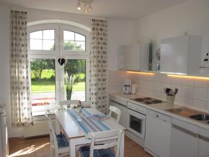 a white kitchen with a table and a window at FeWo ABDENA DORN200 in Dornum